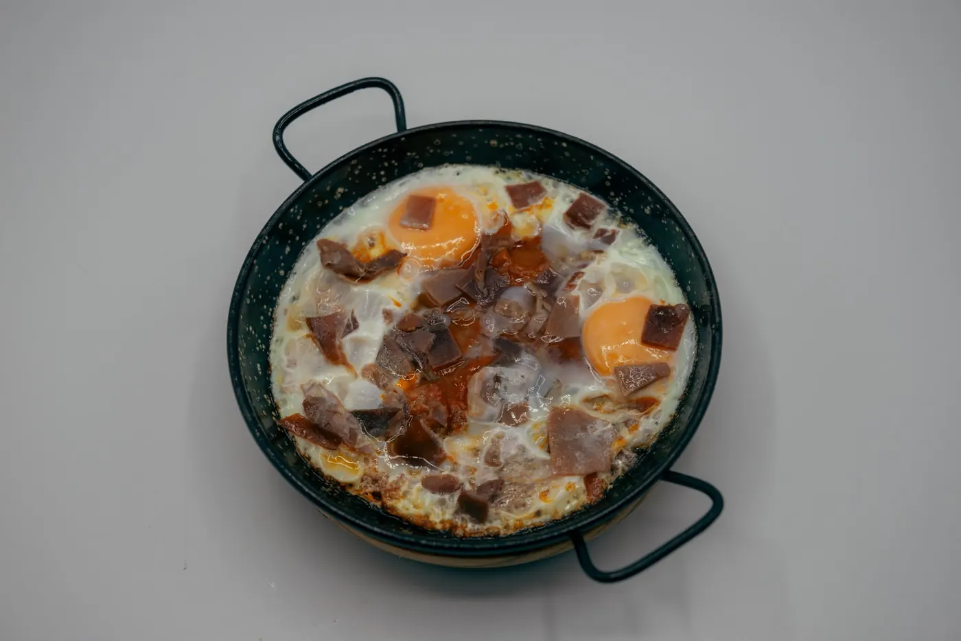 Huevos rotos con jamón servidos en cazuela